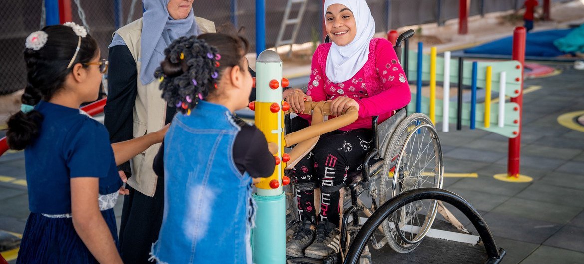 Seorang anak berusia sembilan tahun bermain dengan teman-temannya di jungkat-jungkit di taman bermain inklusif sekolah di kamp pengungsi Za'atari, Yordania.