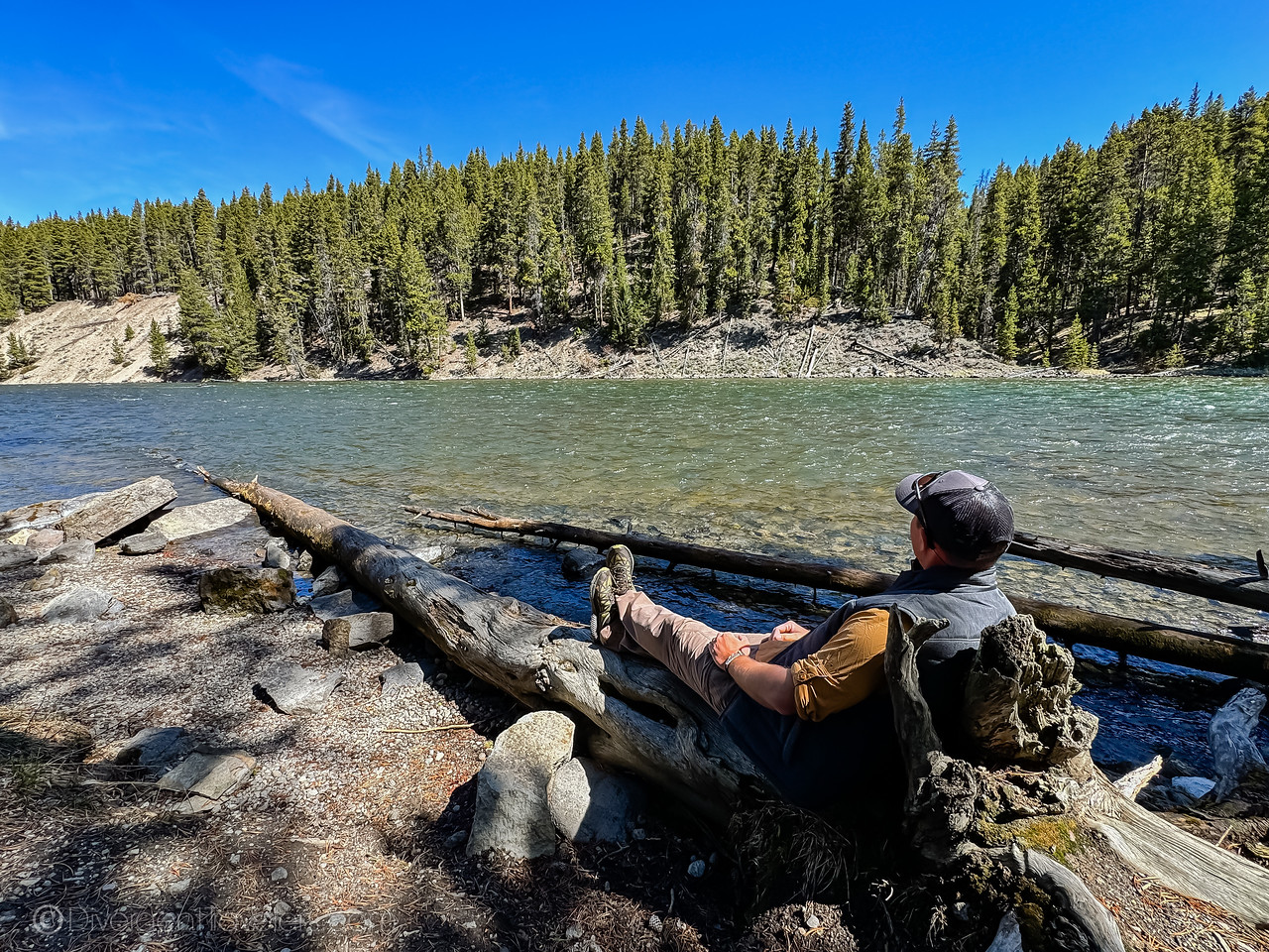 David Stock sitting on a log near the Yellowstone River in Yellowstone National Park