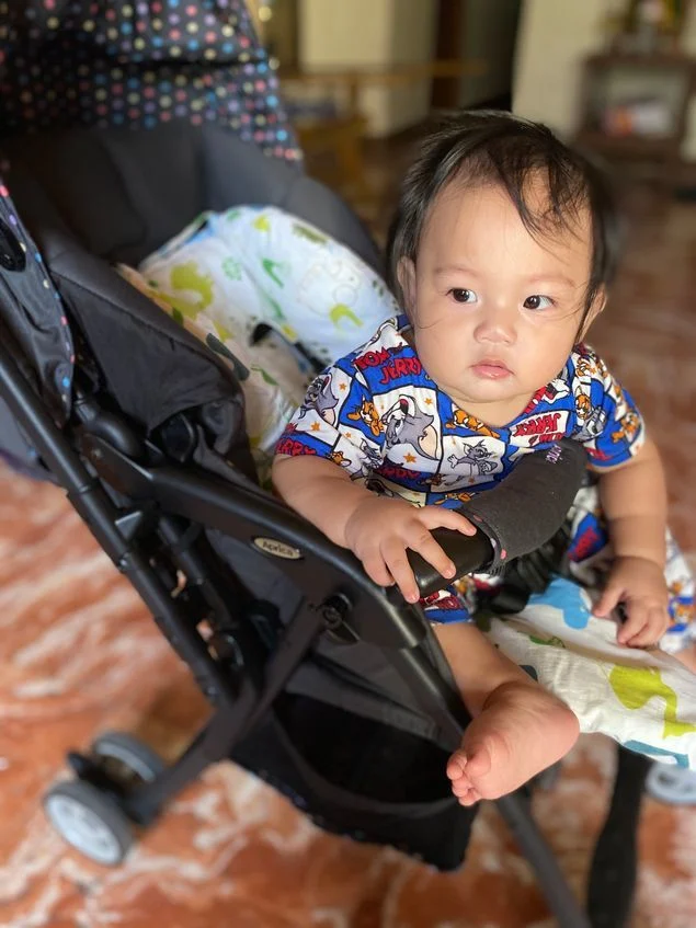 Anak laki-laki kami duduk dengan nyaman di kereta dorong Aprica miliknya