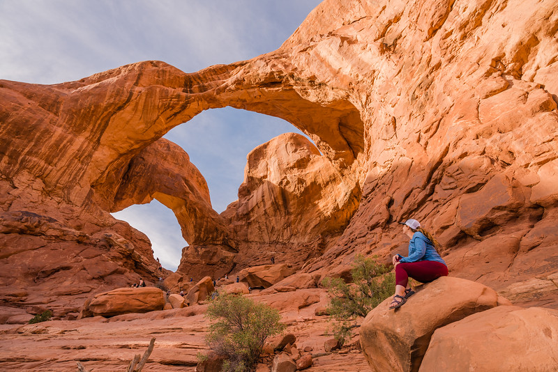 Lina Stock of beragampengetahuan adventure travel blog takin in a moment while viewing the Double Arch in Arches National Park.