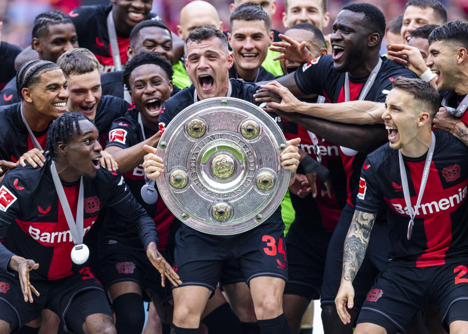 LEVERKUSEN, JERMAN – 18 MEI: Granit Xhaka dari Leverkusen merayakan kemenangan trofi bersama Jeremie Frimpong dari Leverkusen (Kiri), Florian Wirtz dari Leverkusen (3.L), Victor Boniface dari Leverkusen (3.L) dan Alejandro Grimaldo dari Leverkusen di upacara kemenangan setelah pertandingan Bundesliga antara Bayer 04 Leverkusen dan FC. Augsburg di BayArena pada 18 Mei 2024 di Leverkusen. Jerman (Foto oleh Mika Volkmann/Getty Images)