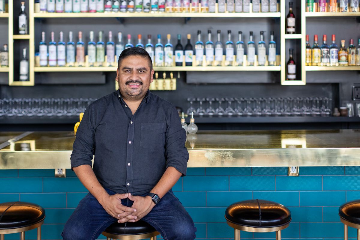 Ivan Vasquez, owner of Madre, sitting on a stool at his Oaxacan restaurant and bar