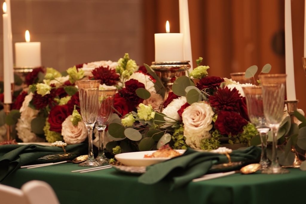 L Prestigious Events LLC merancang meja musim dingin yang menakjubkan dengan warna hijau zamrud, aksen emas mewah, dan lilin romantis. (Berisi bunga yang dirancang oleh sesama anggota grup Desain Bunga dan Acara HTTS!).