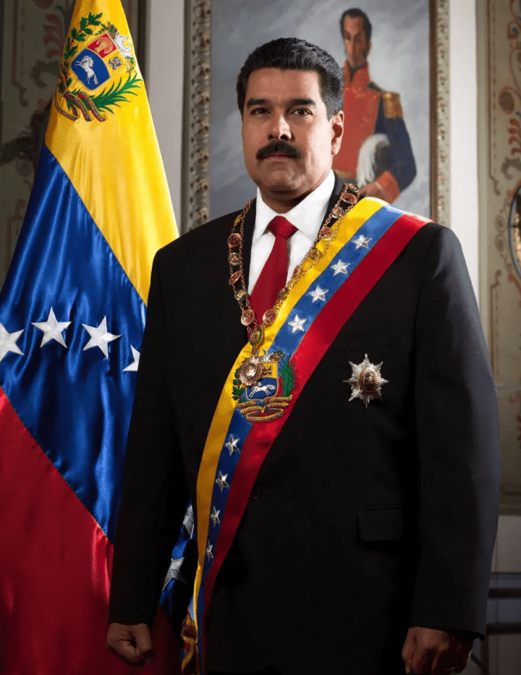 Presiden Venezuela Nicolás Maduro berdiri di sebelah bendera Venezuela.