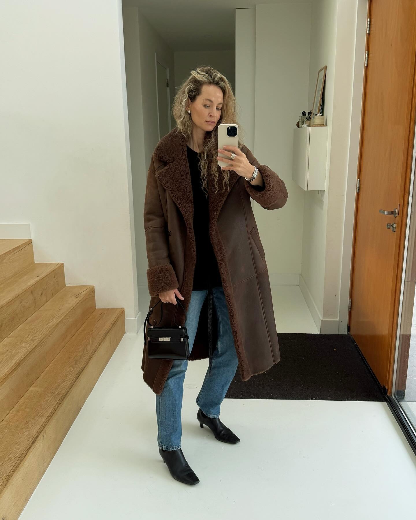 Influencer tersebut mengenakan mantel panjang dengan jeans dan sepatu bot semata kaki.