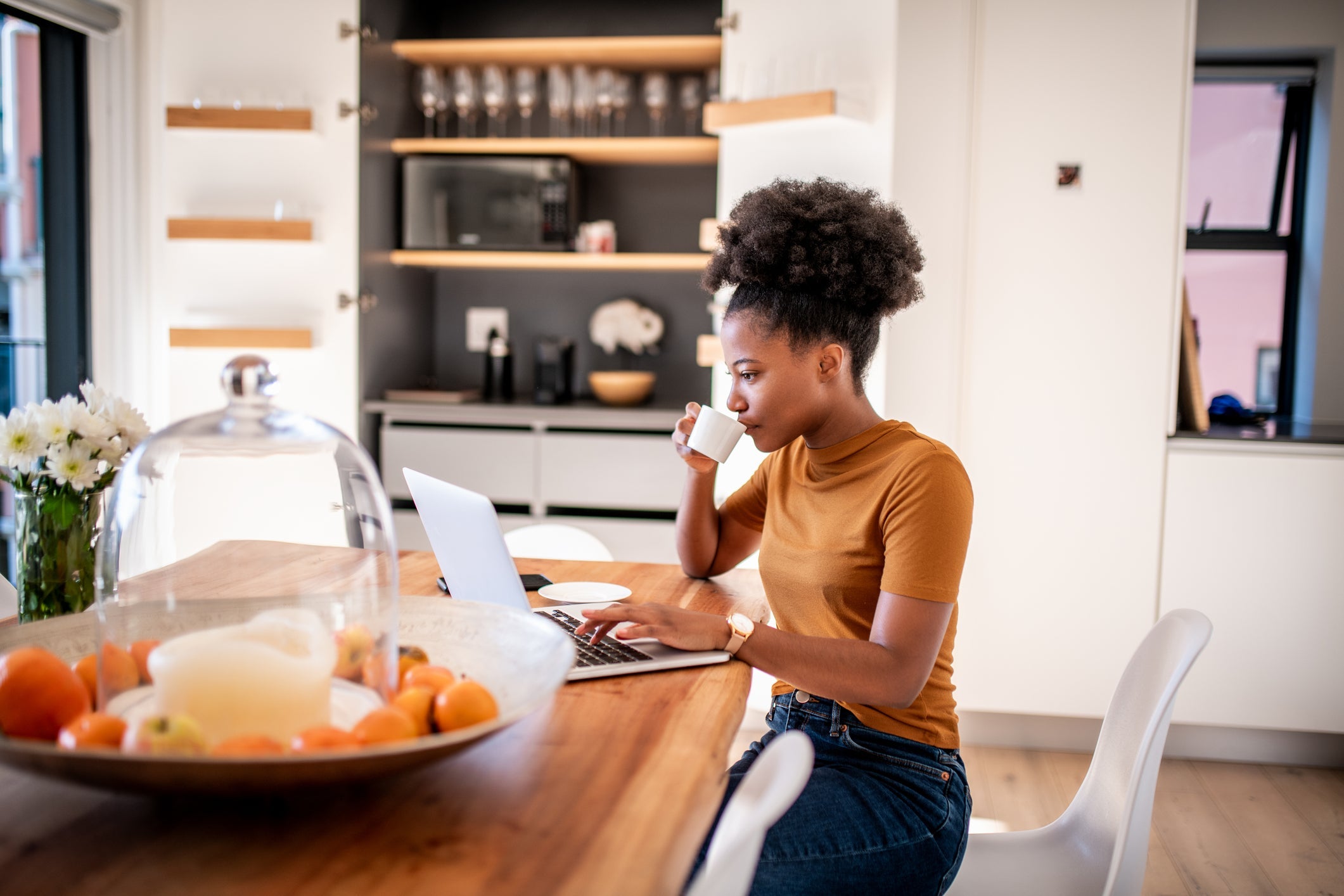 Wanita muda minum kopi dan memeriksa toko online