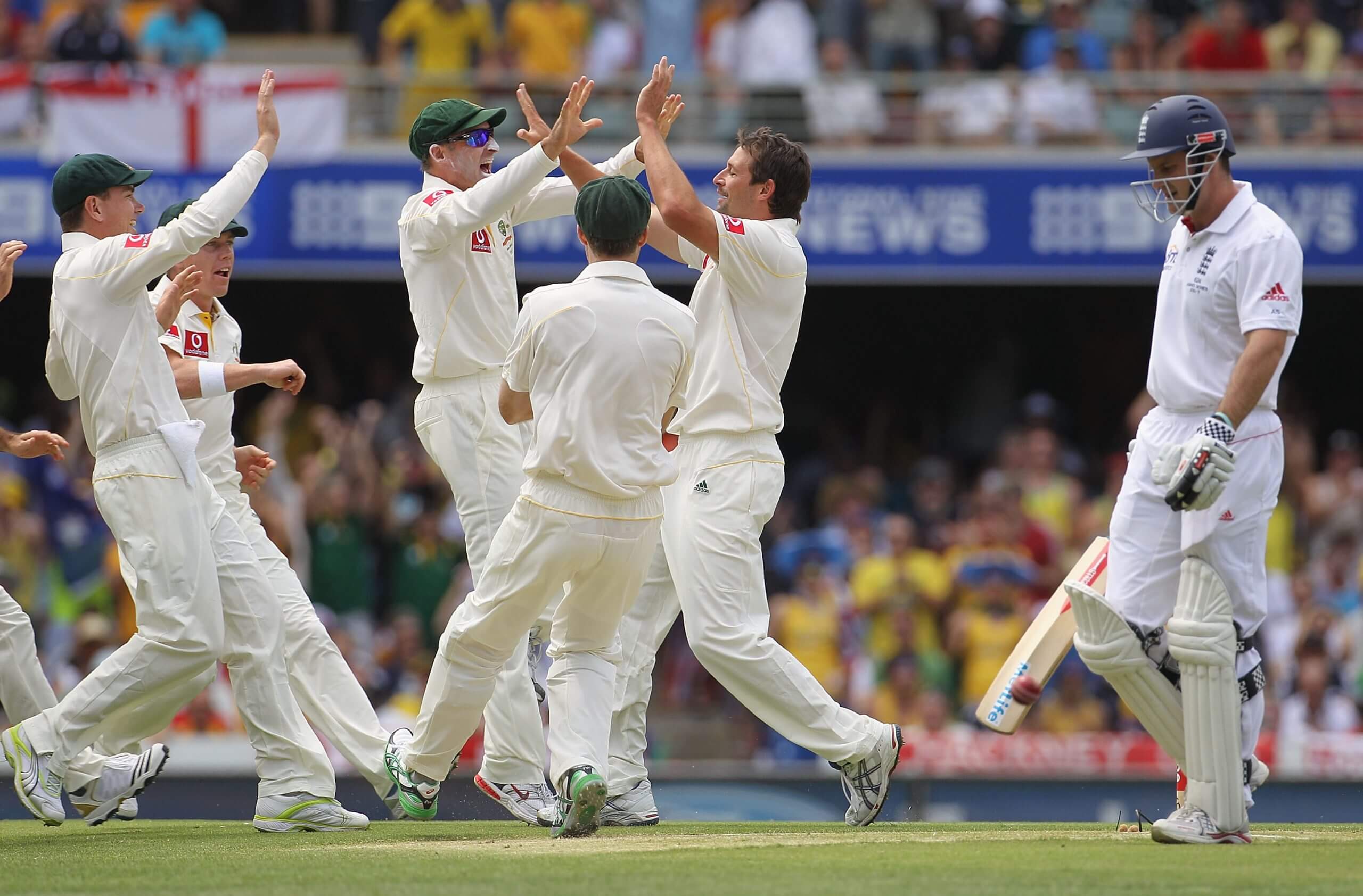 Australia's players converge in celebration as Andrew Strauss trudges off, dismissed third ball